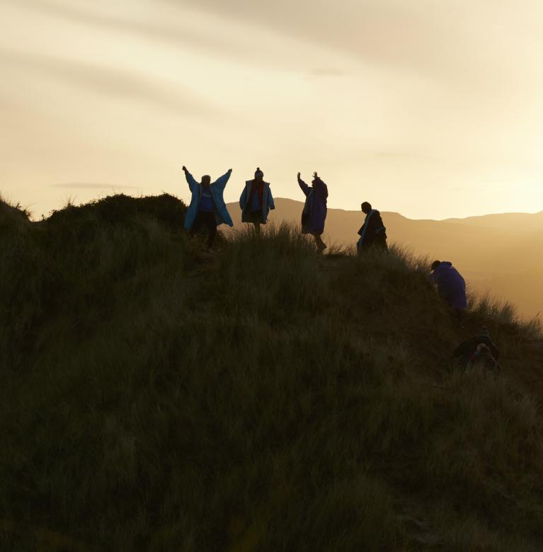 Five climbing a hill silhouetted against a sunrise