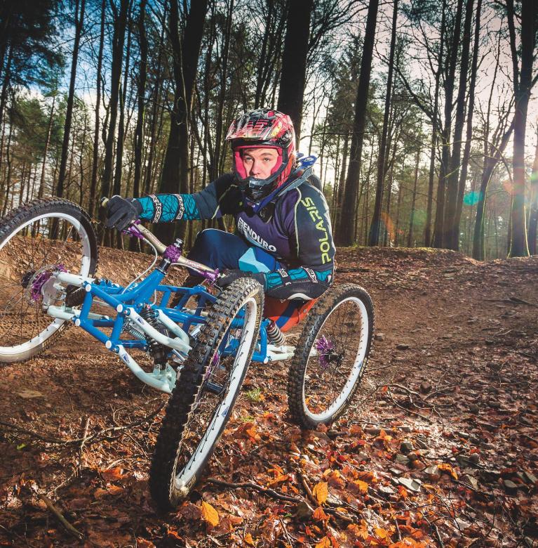 A man in a disability bike on a downhill forest biking course