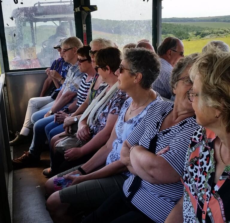 Eine Gruppe von Menschen sitzt auf einem Anhänger und genießt die Aussicht auf einen Bauernhof.