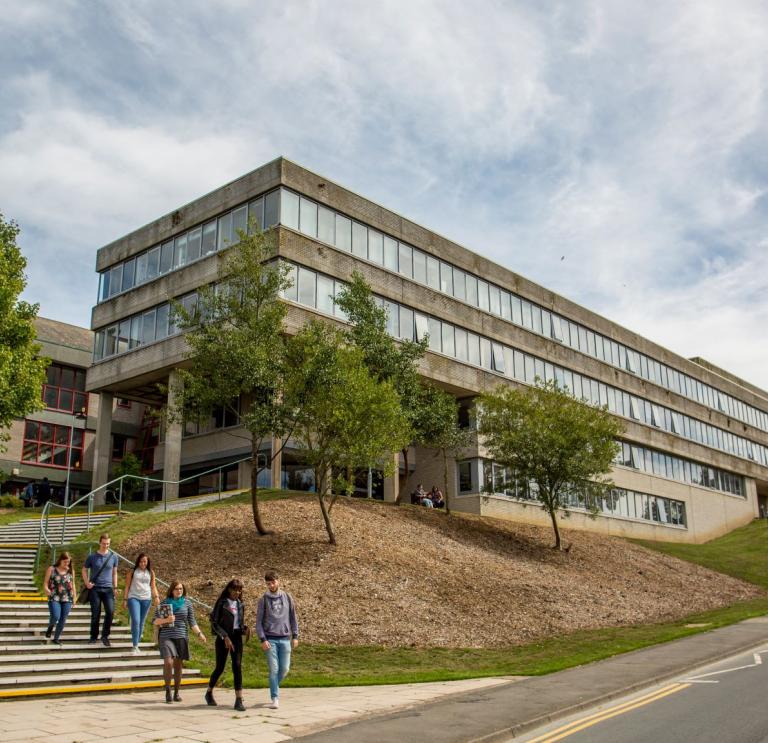 An external view of a university building with students walking down the steps.