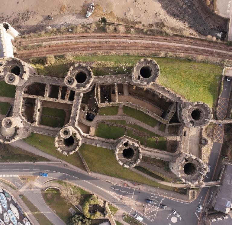 An aerial shot of a castle with a road and railway line running past it.