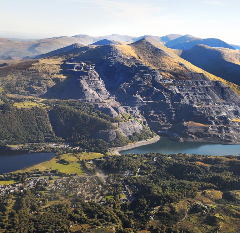 An aerial shot of a slate quarry with blue reservoirs below