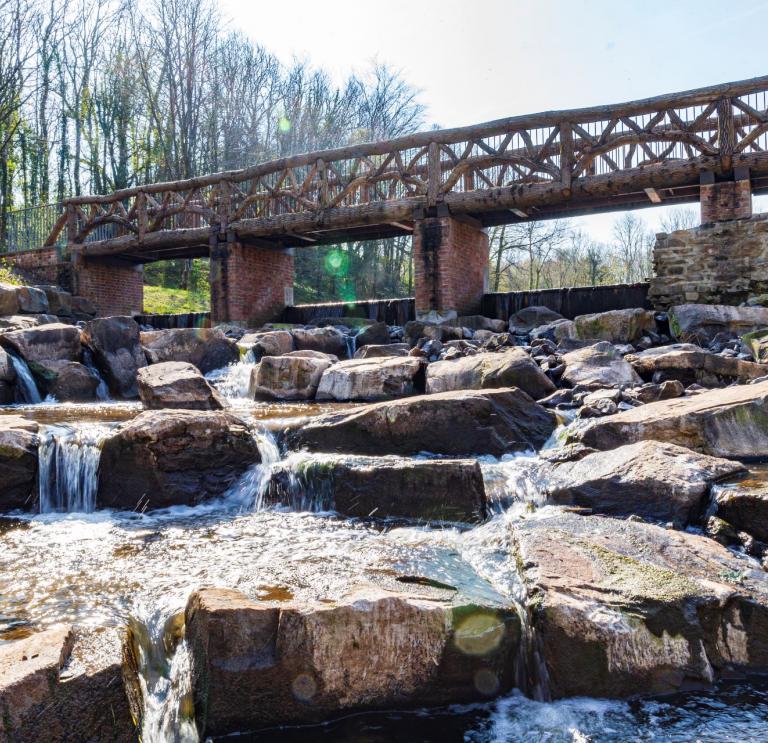 Wasser läuft über Felsen mit einer Brücke darüber.