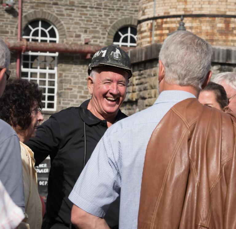 A former miner tour guide laughing with a group of people.