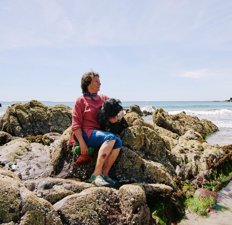 Julia sat on the rocks on Caerfai beach with her dog.