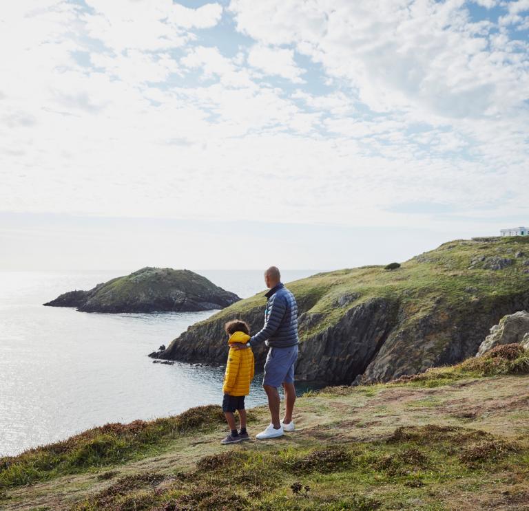 A man and child looking out to sea at Strumble Head, Pembrokeshire. 