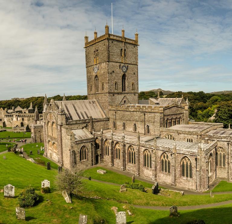A view from a height of St Davids Cathedral with a blue sky and wispy clouds.