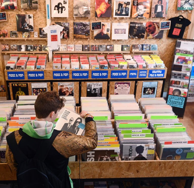 A man looking at a tray full of vinyl records inside a record shop.