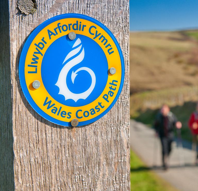 A sign on a post that says Wales Coast Path.