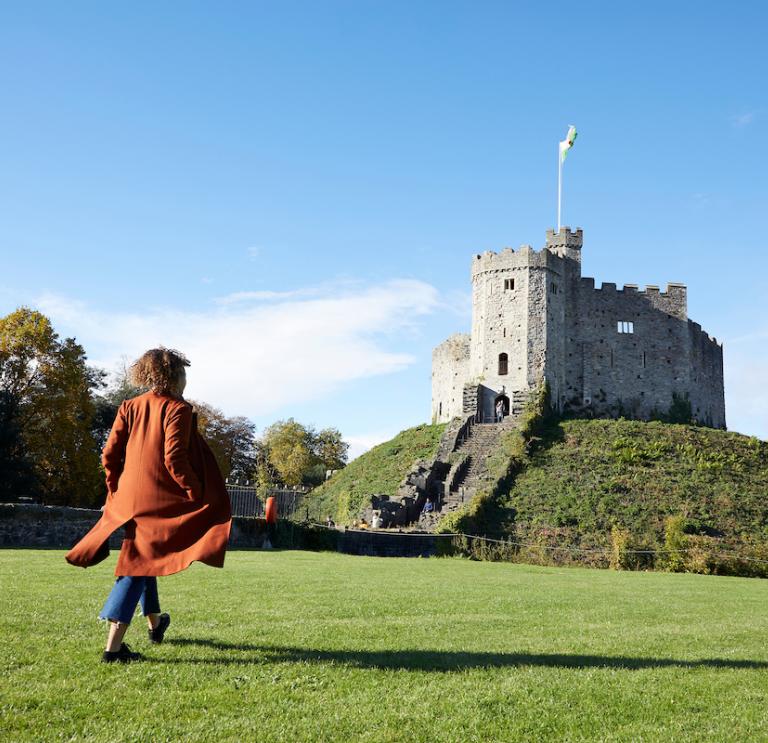 Woman walking towards the Norman Keep at Cardiff Castle 