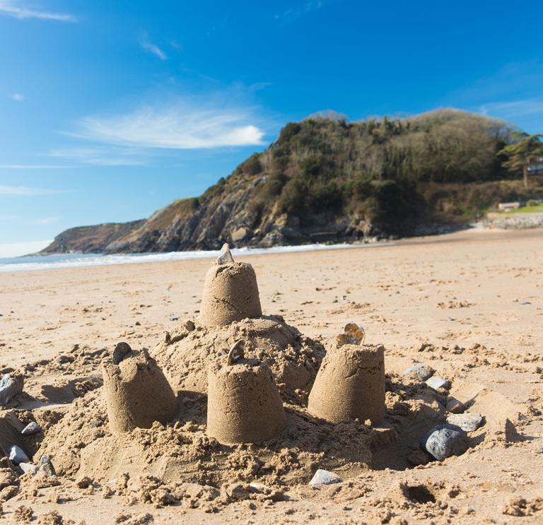Sandcastles on the beach with the sea and sky in the distance.