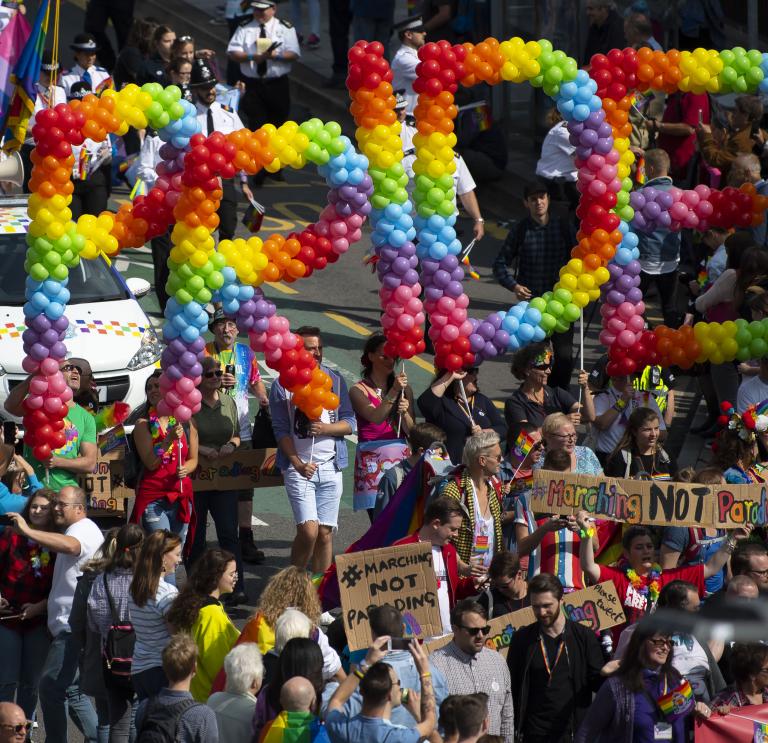 Eine Menschenmenge, die Luftballons mit der Aufschrift „Pride“ (Stolz) hochhält.