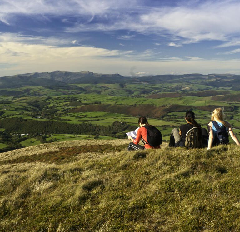 Three female walkers resting on summit of Foel Fadian, looking north to Cader Idris.