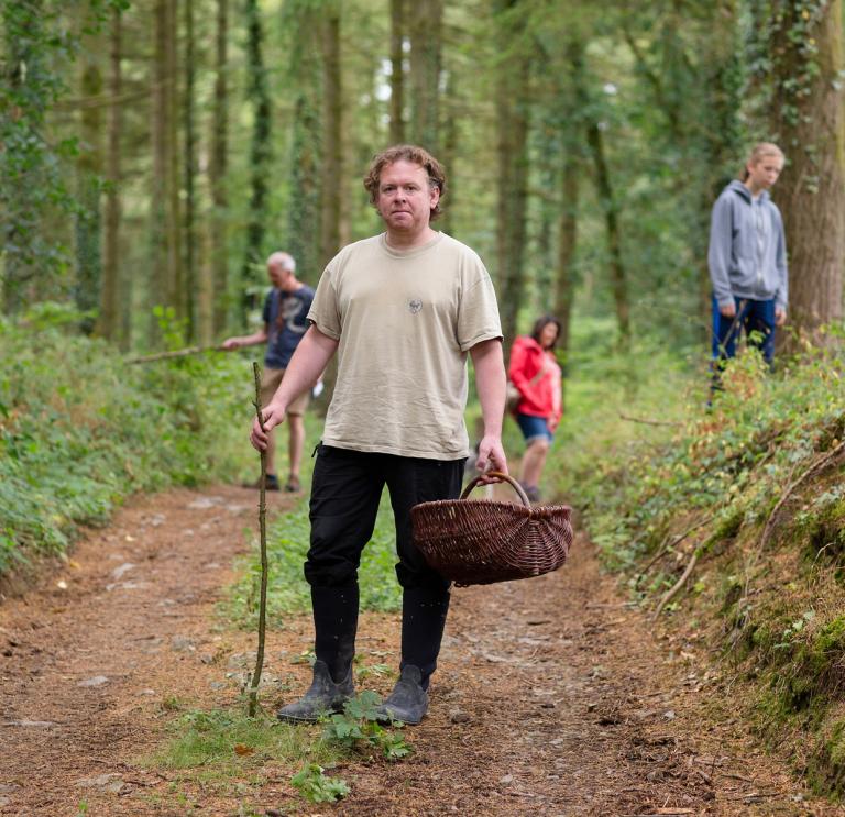 Forager Matt Powell foraging in a wood with some of his clients