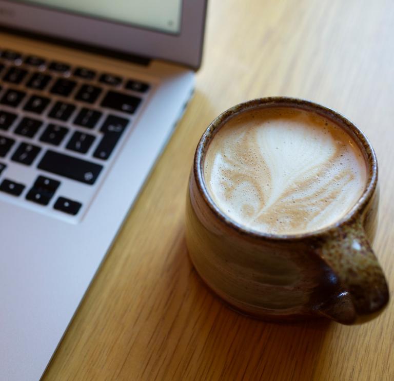 mug of coffee with open laptop computer showing keyboard