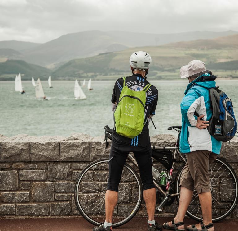 Two cyclists watching yachts.