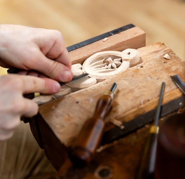 A wooden lovespoon in a vice being carved 