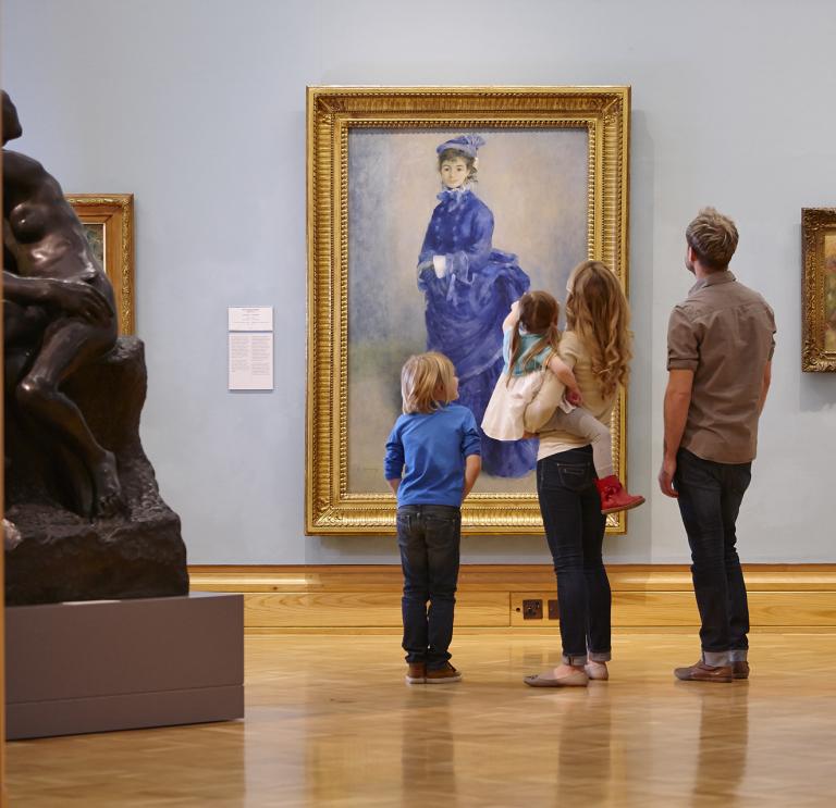 Eine Familie betrachtet ein Gemälde in der Galerie.