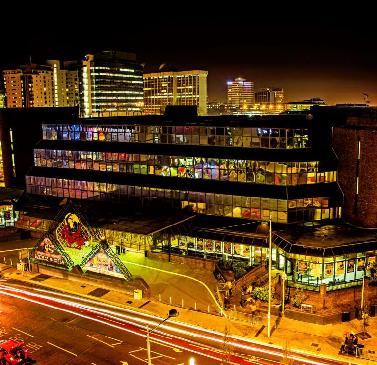 nightime aerial view of the Motorpoint Arena with branded red dragon on glass panel at the front of the building. 