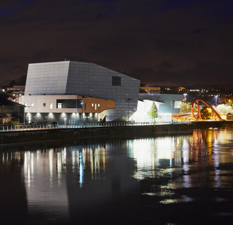 Ansicht des Riverfront Theatre und Arts Centre in Newport erleuchtet bei Nacht.