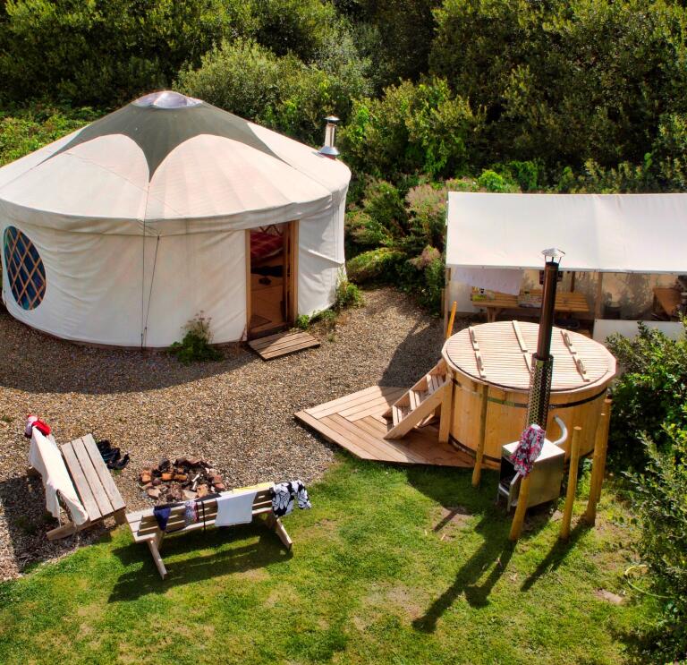 A yurt from above with a hot tub and outside seating.
