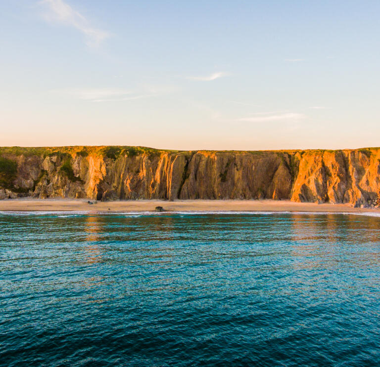 A sunset image of Marloes Cliffs and sea.