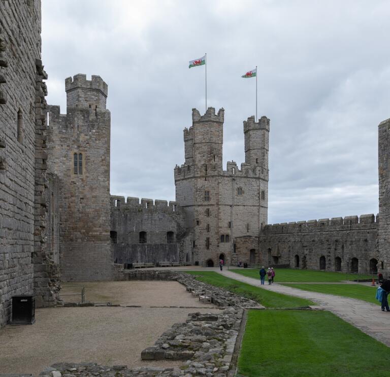 interior castle walls and turrets, with people walking in the courtyard.