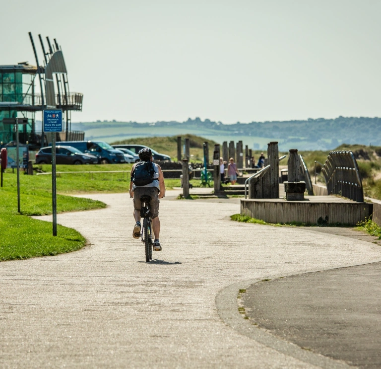 Ein Radfahrer auf einem Radweg mit einem Gebäude im Hintergrund.