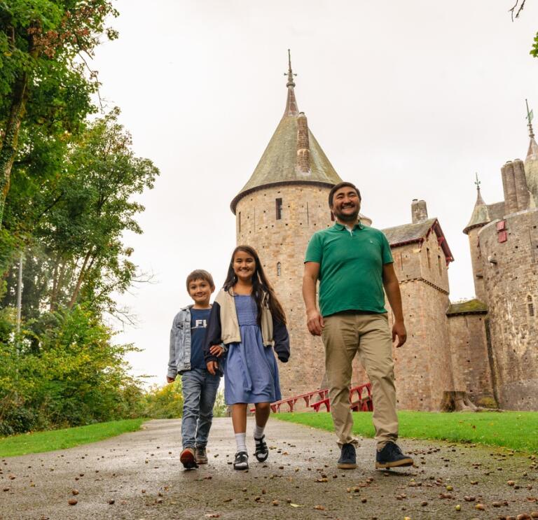 Vater und zwei Kinder spazieren vor einer märchenhaften Burg  