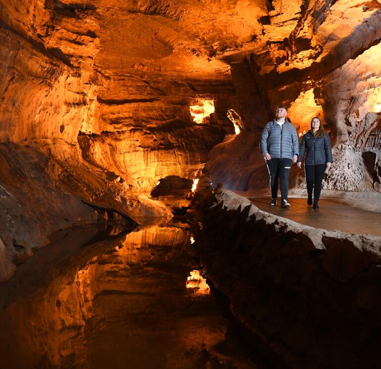 Two people walking along an underground path in a cave.
