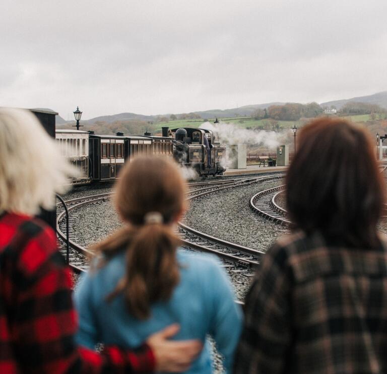 three people looking at a steam train.