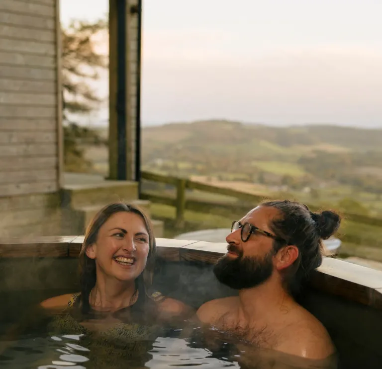 woman and man in hot tub with view of countryside.