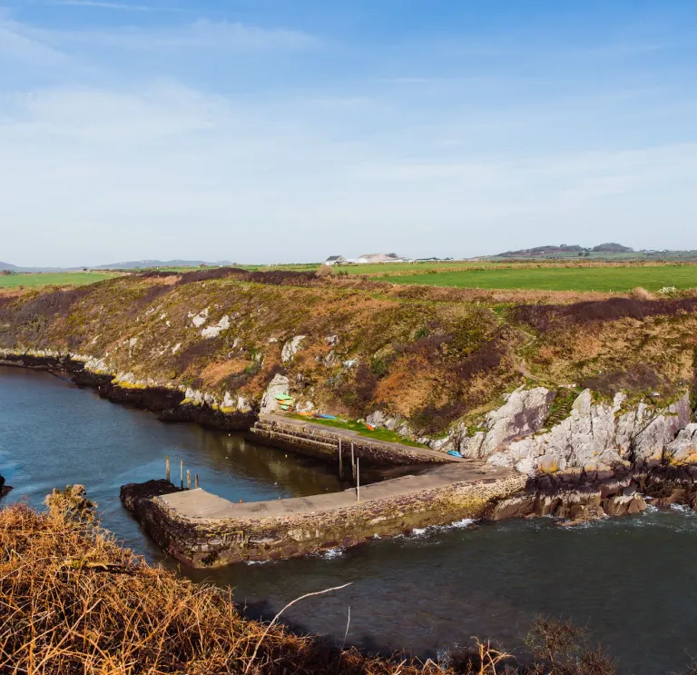 A small harbour surrounded by cliffs with the tide in.