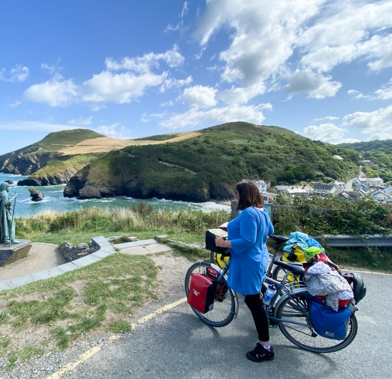 woman standing with bike looking out over the sea.