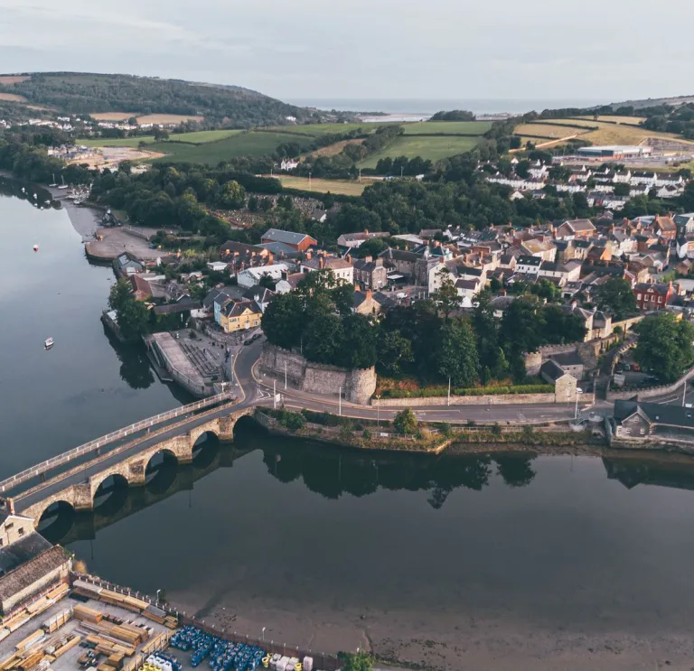 Aerial view of a town by a river, with a stone bridge and castle. 