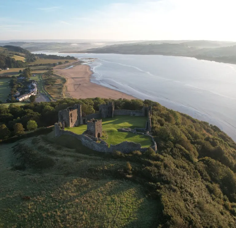 Aerial view of castle  high above coast with views of sea and countryside.