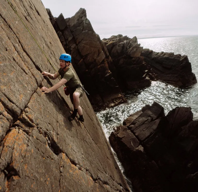 climbing wearing helmet climbing sea cliff.