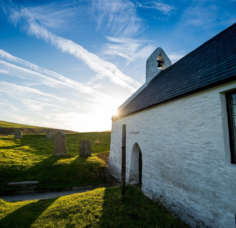 Sunny image of the side of a small whitewashed church.
