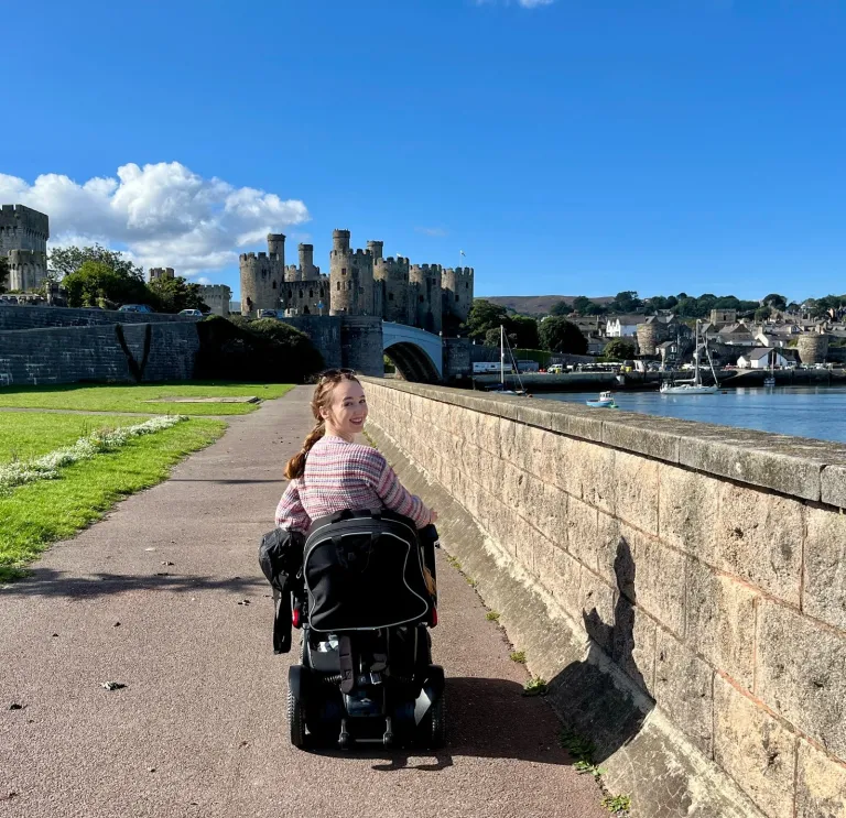 woman on motorised wheelchair with castle in background.