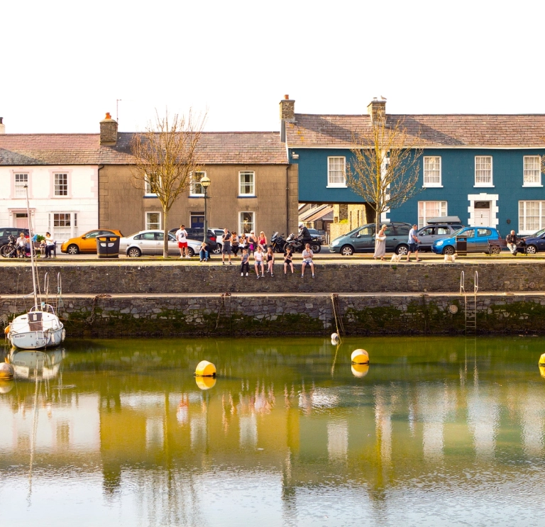 people sat on wall, Aberaeron harbour.