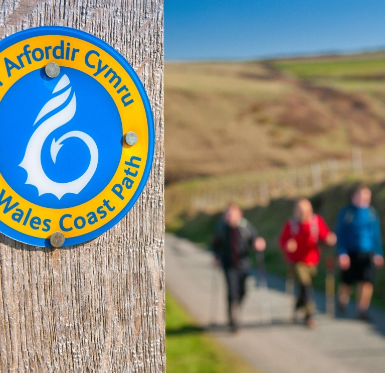 A sign on a post that says Wales Coast Path.