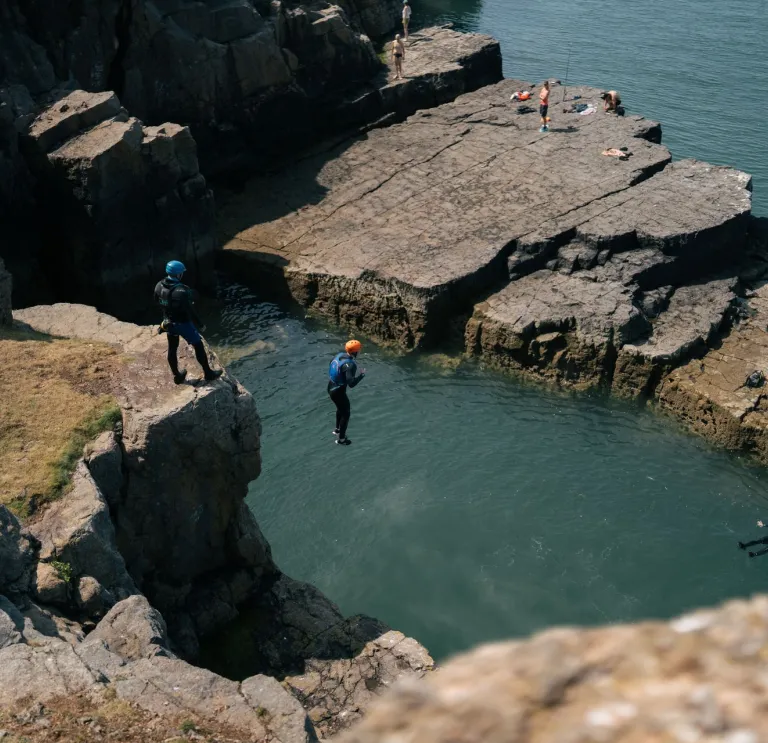 Coasteering - a person jumping into the sea from a cliff.
