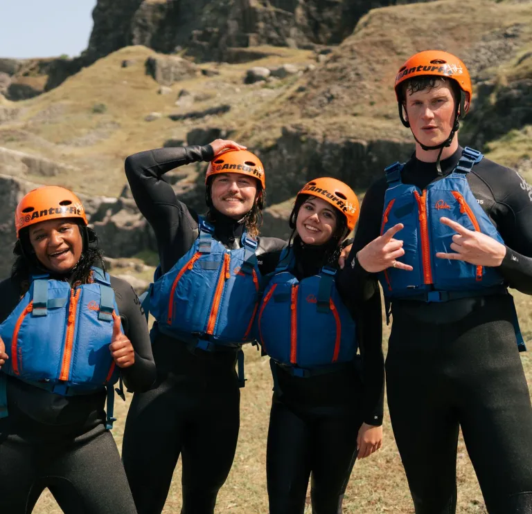 Four people in coasteering kit looking very happy. 