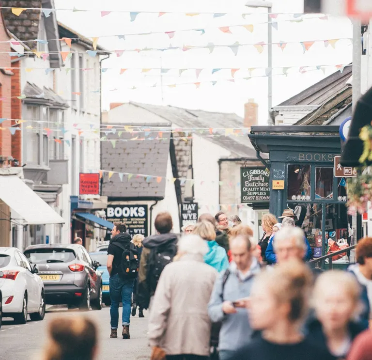 Visitors strolling through Hay-on-Wye during a lively day, with bookshops and bunting lining the street