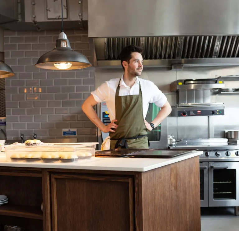 Person preparing food at a kitchen island in a modern restaurant kitchen.