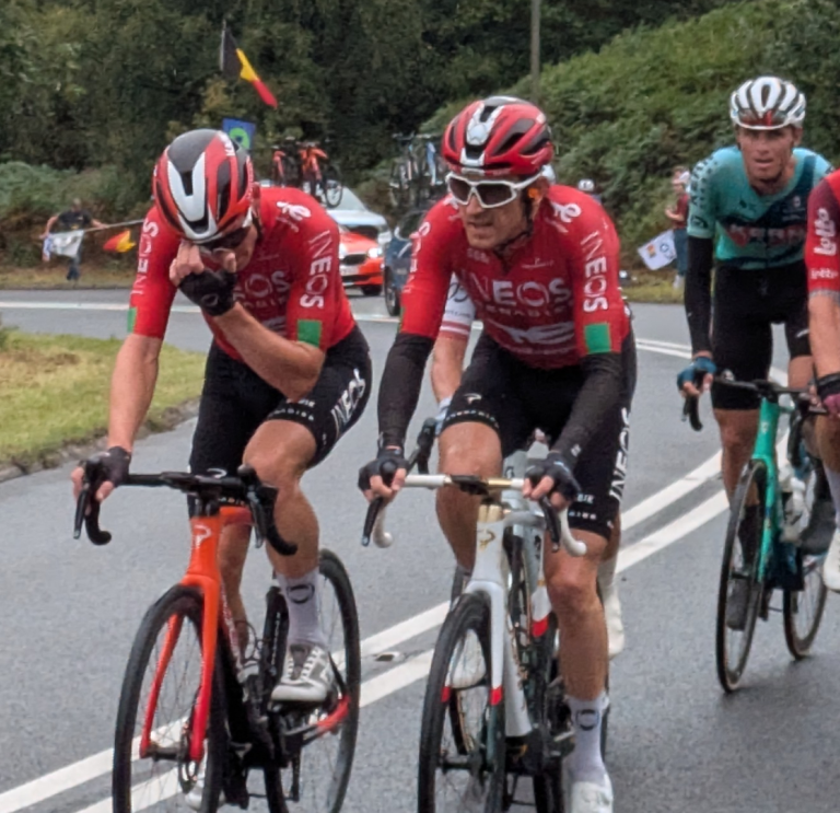 Gruppe professioneller Rennradfahrer mit Geraint Thomas im Vordergrund auf einer Straße in der grünen Landschaft.