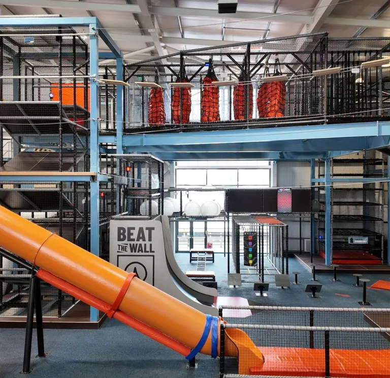 An indoor high ropes/assault course with slides, climbing frames and wires.