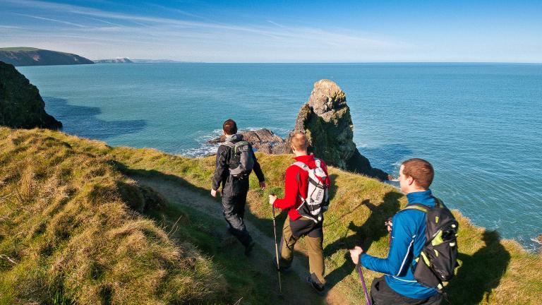 Three male walkers on Wales Coast Path, Pembrokeshire, West Wales