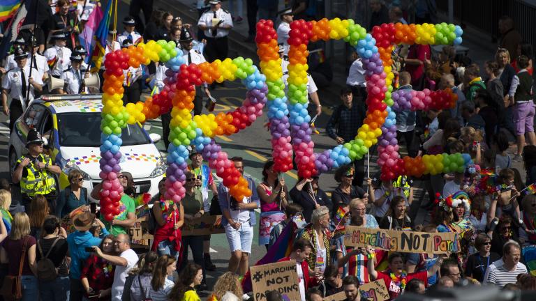 Eine Menschenmenge, die Luftballons mit der Aufschrift „Pride“ (Stolz) hochhält.