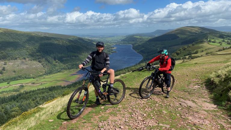 Two people on mountain bikes overlooking a lake.